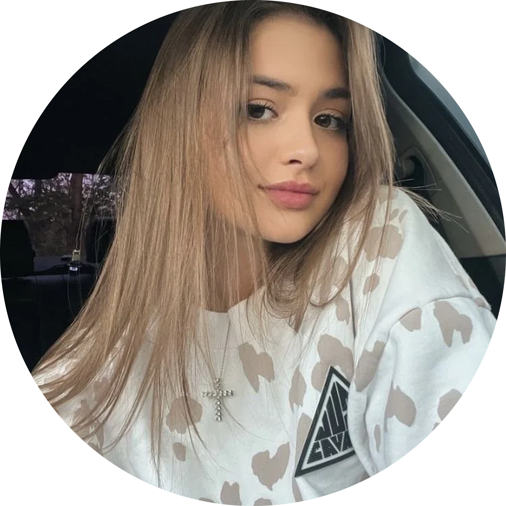 Person wearing a camouflage-patterned shirt with a brand logo, sitting inside a vehicle.